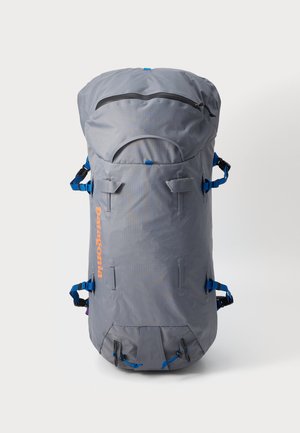 Szürke hátizsák kerek tetejű, kék pántokkal és narancssárga logóval. Zipzáras zsebbel és több rögzítési lehetőséggel rendelkezik. Tartós anyagból készült.