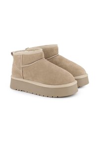 Botas de tobillo de ante beige con puntera redondeada, que cuentan con un forro suave, suela beige y sutiles acentos cosidos alrededor de la parte superior.
