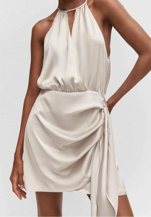 Robe mini en satin beige sans manches, avec un col halter, une taille froncée et un détail de ceinture drapée sur un côté.