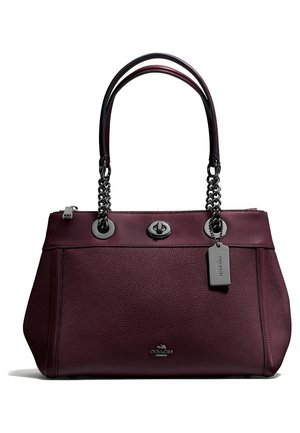 Sac à main en cuir violet foncé avec double chaîne et poignées en cuir, fermeture à loquet tournant à l'avant, et étiquette logo en métal attachée à une poignée.