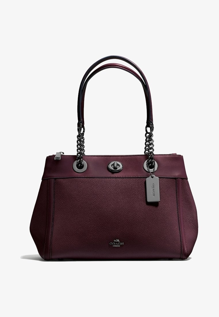 Sac à main en cuir violet foncé avec double chaîne et poignées en cuir, fermeture à loquet tournant à l'avant, et étiquette logo en métal attachée à une poignée.