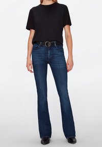 Black short-sleeve t-shirt paired with dark blue flared jeans and a black belt featuring a circular silver buckle. Smooth, casual fabric texture.