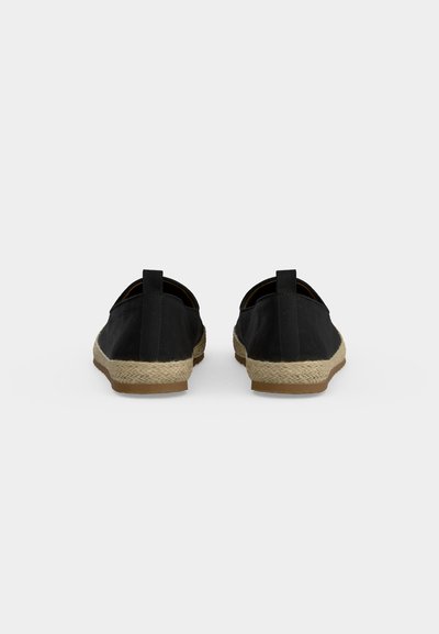 Paire de chaussures espadrilles noires à enfiler avec semelles enveloppées de jute, vues de dos sur un fond clair uni.