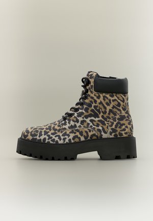 Støvle med høj skaft med sort sål, sort polstret ankelkrave, sorte snørebånd og brun og sort leopardmønstret print.