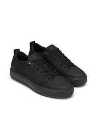 Un paio di sneaker nere a bassa cima con design lacciato e suole in gomma spessa, esposte su sfondo bianco.