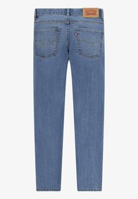 Modré denimové džíny se rovnými nohavicemi, designem s pěti kapsami a hnědou koženou nášivkou na zadním pásku. Zpevněné švy.