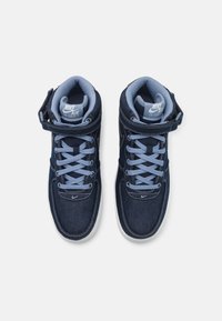 Vysoké tenisky Nike Air Force v tmavě modrém denimu, s světle modrými tkaničkami, suchým zipem a bílou gumovou podrážkou.