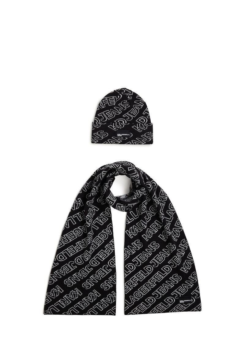 Black knit scarf and beanie set featuring repeating white text pattern. Soft texture, structured shape, with logos displayed prominently.