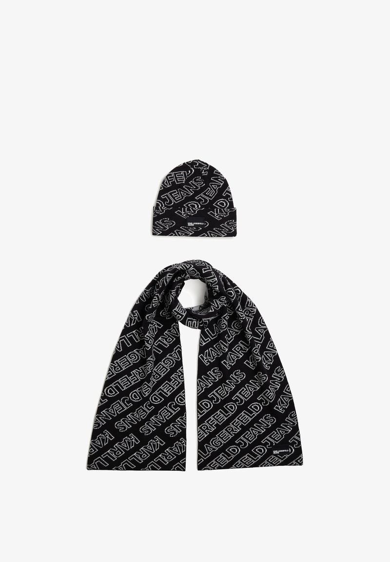 Black knit scarf and beanie set featuring repeating white text pattern. Soft texture, structured shape, with logos displayed prominently.