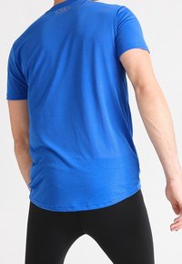 Camiseta deportiva azul con cuello redondo, mangas cortas y una textura suave, con sutiles rayas horizontales en la tela.