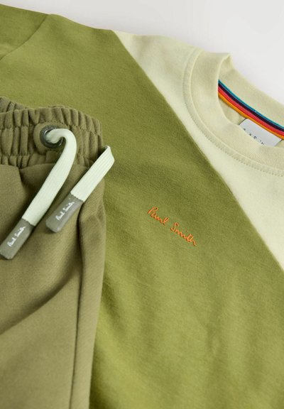Grøn og cremefarvet farveblok-shirt med orange "Paul Smith"-logo og matchende grønne snøre bukser med mærkede ender.