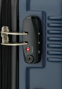 Lucchetto TSA approvato nero su una valigia blu e grigia con texture, caratterizzato da maggiori tiranti metallici e un distintivo logo a forma di diamante.