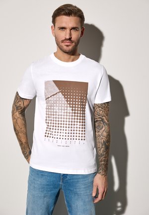Camiseta de algodón blanca con un gráfico marrón que presenta diferentes patrones de puntos y texto. Mangas cortas, cuello redondo, ajuste casual.