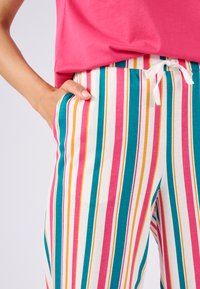 Gestreepte katoenen broek met verticale strepen in roze, teal en geel, voorzien van een elastische tailleband en witte trekkoord; zijzakken zichtbaar.