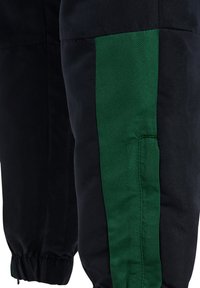 Czarne spodnie z elastycznymi mankietami, z pionowym ciemnozielonym paskiem wzdłuż zewnętrznej strony nogawki.