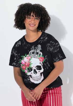 Zwart graphic t-shirt met een grote schedel omringd door roze rozen en een kroon, met een versleten textuur. Gecombineerd met rode gestreepte broek.