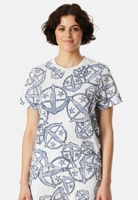 Weißes T-Shirt mit einem blauen abstrakten Muster aus Kreisen und Sternen. Kurze Ärmel, runder Ausschnitt und entspannter Schnitt.