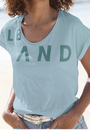 Lyseblå t-shirt med korte ærmer og store grønne bogstaver. Glat stof og afslappet pasform, kombineret med et vævet hvidt bælte.