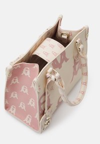 Sac à main à motifs crème et rose avec ferrures dorées, ouverture sur le dessus et une seule anse, sur fond blanc.