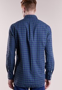 Långärmad skjorta i blå och grön rutig mönster, med button-down krage, knäppta ärmslut och rak ryggsömn. Mjuk bomullstyg.