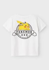 Camiseta blanca con un diseño impreso de Pikachu y el texto "POKÉMON" y "¡Atrápalos a Todos!" en colores negro y amarillo.