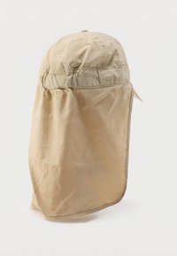 Μπεζ καπέλο ηλίου με απαλό, ελαφρύ ύφασμα, καμπύλη γείσο και επεκταμένο πίσω μέρος για κάλυψη του λαιμού. Διαθέτει ρυθμιζόμενο ελαστικό κορδόνι.