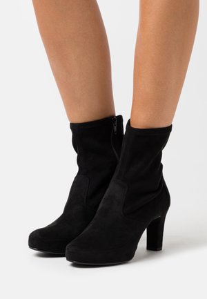 Stivaletti alla caviglia in camoscio nero con design aderente, dotati di zip laterale e tacco a blocco. Il materiale strutturato offre una finitura morbida.