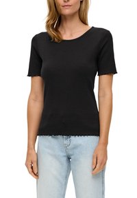 Zwarte top met korte mouwen van ribstof, met een ronde halslijn en een golvende zoom. Gepaard met lichtblauwe jeans.