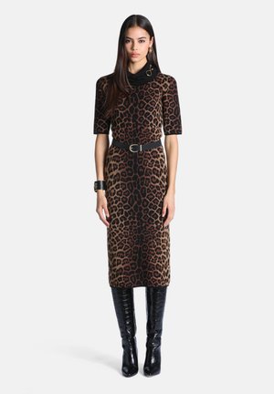 Femme portant une robe imprimé léopard mi-longue avec ceinture noire, bracelet manchette noir, boucles d'oreilles dorées et bottes noires montantes jusqu'aux genoux.
