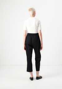 Pantalons noirs à taille élastique avec un design court, assortis à un haut ajusté à manches courtes blanc. Tissu lisse avec une silhouette classique.