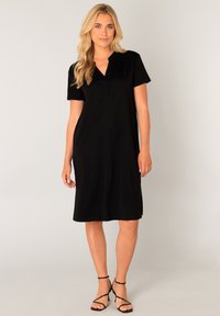 Zwarte jurk met korte mouwen en een V-hals, gemaakt van zachte stof, met een ontspannen pasvorm die net boven de knie valt.