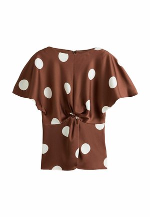Blouse marron à manches courtes avec de grands pois blancs et un nœud torsadé au niveau de la taille dans le dos.