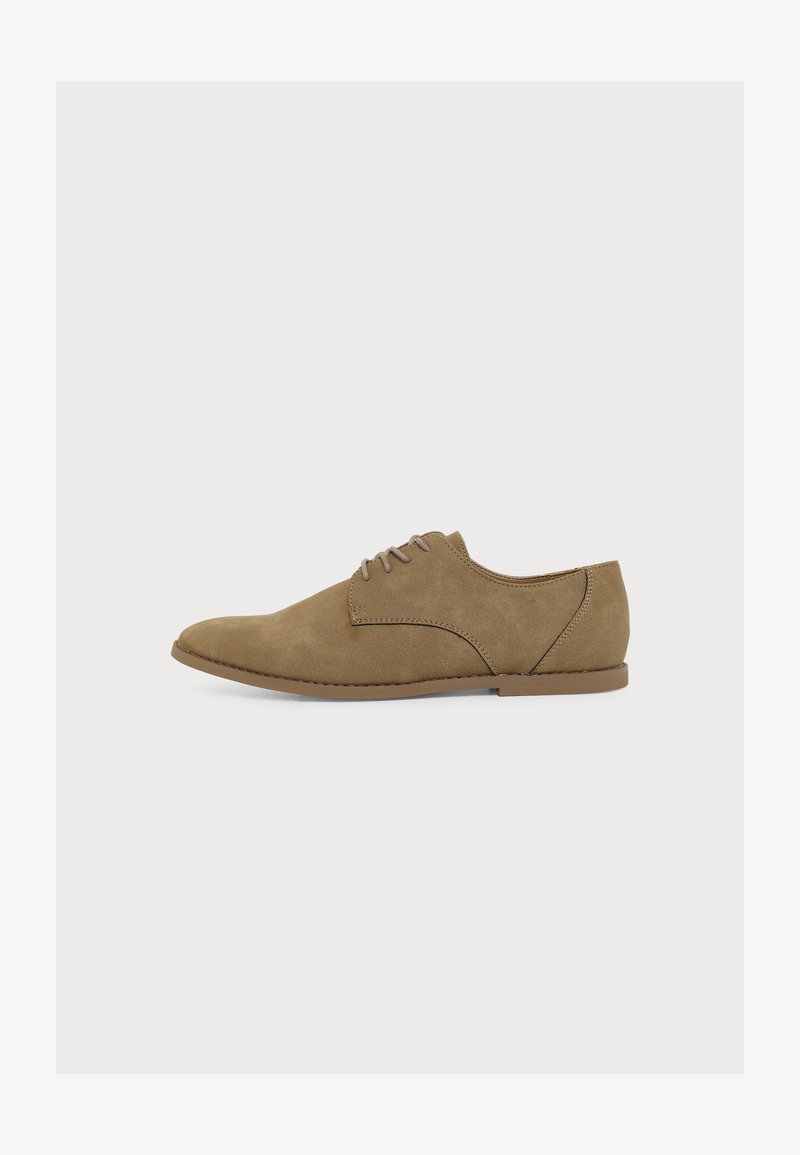 Chaussure Oxford en daim marron à lacets avec semelle plate et bout arrondi, vue de côté sur un fond clair uni.