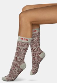 Kniestrümpfe aus weichem, gestricktem Material mit einem roten geometrischen Muster auf hellem Grau und mit gerippten Bündchen.