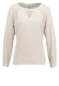 Blouse beige clair à manches longues avec des accents en dentelle au niveau de l'encolure et des épaules, texture lisse, col rond, et coupe décontractée.