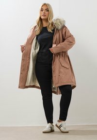 Huppari vaaleanpunaisena, jossa on tekoturkisreunus, pehmeä kerma sisustus, vyötäröltä kiristetty malli ja sivutaskut. Yhdistetty mustiin housuihin ja tennareihin.