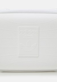White textured pouch with a raised white Adidas logo and three-stripe insignia. Smooth finish with subtle pattern details on the surface.