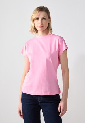 Lyserød kortærmet T-shirt lavet af bomuld med rund halsudskæring og afslappet pasform, parret med mørke jeans. Glat tekstur, minimal design.