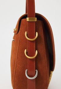 Tote tas van roestbruin suede met een gestructureerde vorm. Voorzien van een brede leren schouderband met gouden en zilveren hardwareaccenten en een textuurdesign.