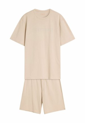 Beżowy zestaw odzieży domowej z bawełny, składający się z koszulki z krótkim rękawem z wytłoczonym tekstem oraz dopasowanych spodenek z elastycznym pasem.