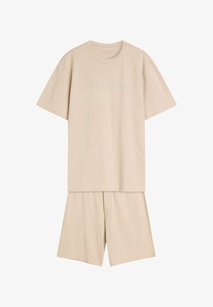 Beżowy zestaw odzieży domowej z bawełny, składający się z koszulki z krótkim rękawem z wytłoczonym tekstem oraz dopasowanych spodenek z elastycznym pasem.
