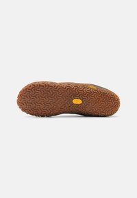Rāvējo zābaku zole ar zigzaga rakstu, kas ir tan krāsā un ar Vibram logo dzeltenā krāsā. Gludas malas un teksturēta virsma, lai nodrošinātu saķeri.