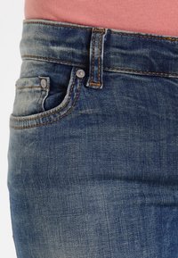 Denimjeans med en bleknad blå tvätt, med en traditionell femfickdesign, böjda sömdetaljer och kopparstickningar.