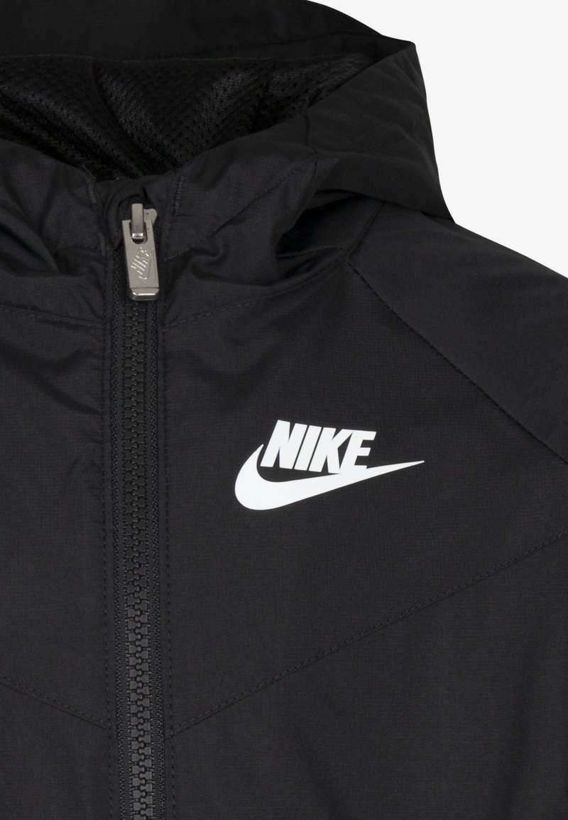 Czarna kurtka Nike z zamkiem błyskawicznym z przodu, z białym logo na piersi i teksturowanym materiałem wewnętrznym. Smukły, lekki design.