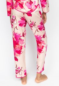 Florale pyjama set met gedurfde roze en crème patronen, soepel stof, lange mouwen en recht gesneden broeken met contrasterende roze biezen.
