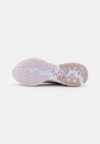 Suola della scarpa con un design multi-texturato, base bianca e accenti rosa, che presenta contorni curvi e modelli di battistrada flessibili.