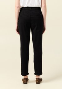 Czarne spodnie z dopasowaną talią, o prostym kroju i podwiniętych mankietach. Miękka bawełniana tkanina, minimalistyczny design i tylne kieszenie.