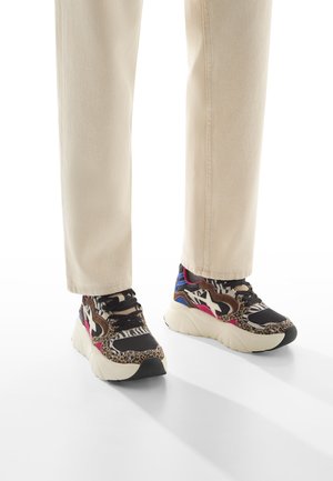 Sneakers chunky con un mix di stampa animale e motivi a righe, con tonalità di nero, marrone e rosa, e una spessa suola bianca.