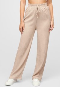 Pantalons larges texturés beiges avec une taille élastique à cordon de serrage, présentant un design en tissu froissé et une coupe loose.