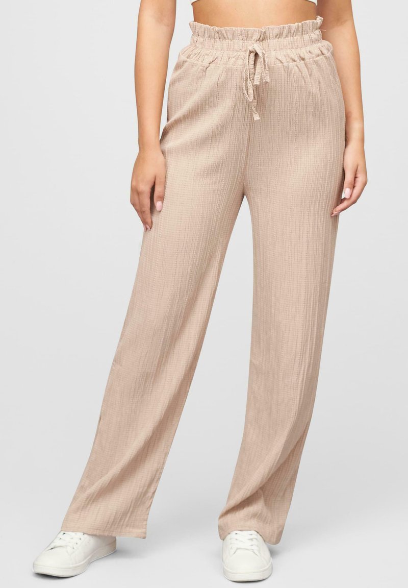 Pantalons larges texturés beiges avec une taille élastique à cordon de serrage, présentant un design en tissu froissé et une coupe loose.
